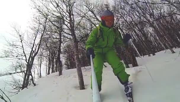 Skier going downhill  with camera on his helmet and in hand — Stock Video