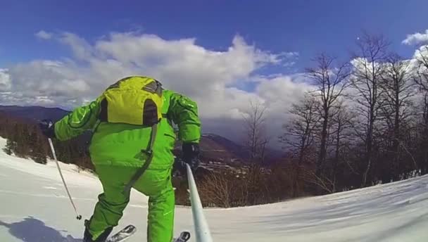 Лыжник спускается вниз с камерой на шлеме и в руке — стоковое видео