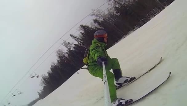 Skier going downhill  with camera on his helmet and in hand — Stock Video