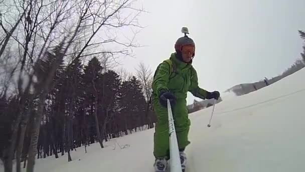 Skier going downhill  with camera on his helmet and in hand — Stock Video