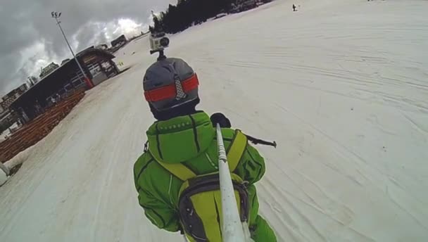 Esquiador va cuesta abajo con cámara en el casco y en la mano — Vídeos de Stock