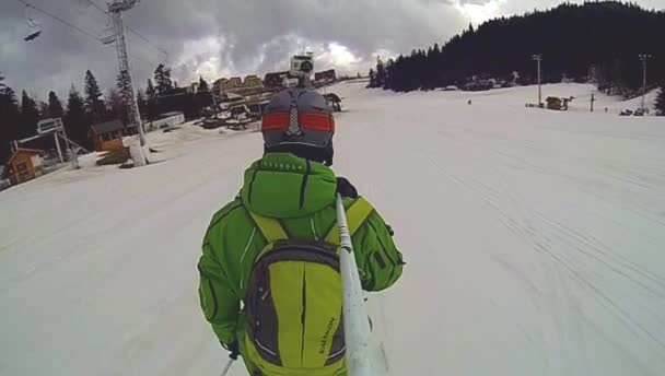 Skier going downhill  with camera on his helmet and in hand — Stock Video