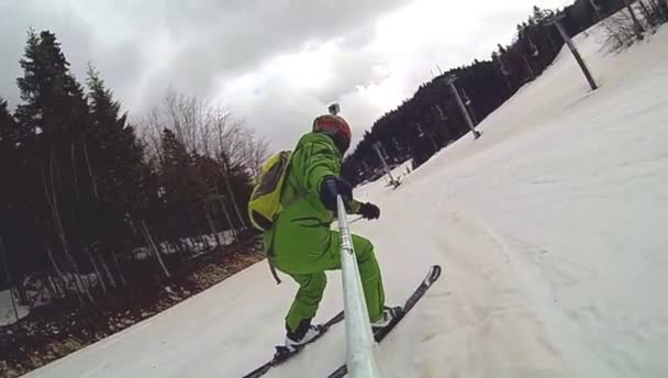 Lyžař jede z kopce s kamerou na helmě a v ruce — Stock video