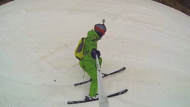 Lyžař jede z kopce s kamerou na helmě a v ruce — Stock video