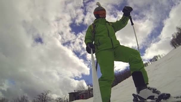Лыжник спускается вниз с камерой на шлеме и в руке — стоковое видео