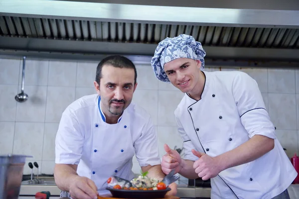 Dois chefs com refeição de peixe na cozinha moderna — Fotografia de Stock