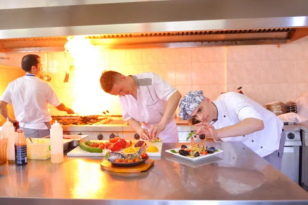 群帅厨师穿着白色的制服 装饰在现代厨房的意面沙拉和海鲜餐 — 图库照片