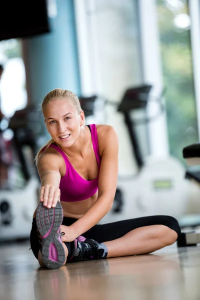 Woman stretching and warming up at a gym — Stock Photo, Image