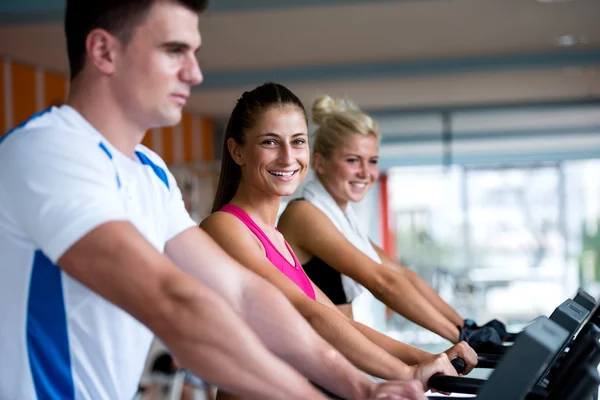 Vrienden uitoefenen op een loopband op de sportschool — Stockfoto