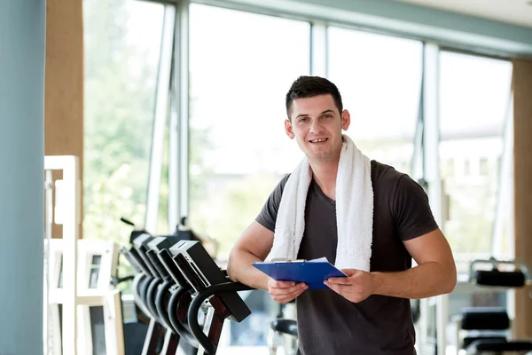 Entrenador con portapapeles de pie en un gimnasio luminoso —  Fotos de Stock