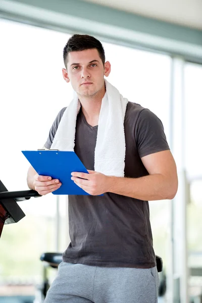 Entrenador con portapapeles de pie en un gimnasio luminoso —  Fotos de Stock