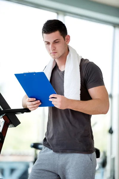 Entrenador con portapapeles de pie en un gimnasio luminoso — Foto de Stock