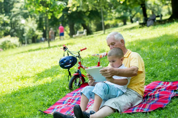 Abuelo y el niño en el parque usando la tableta —  Fotos de Stock
