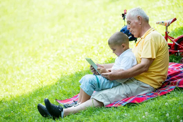 Grandfather and child in park using tablet — Stock Photo, Image