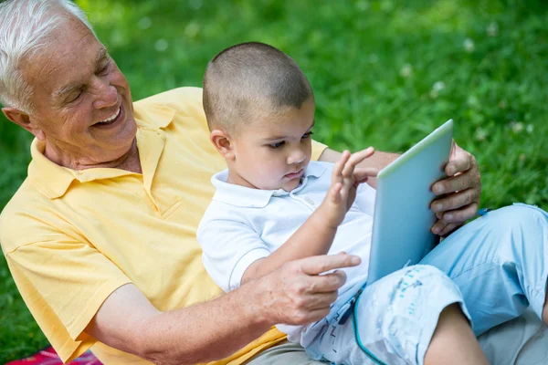 Grandfather and child in park using tablet — Stock Photo, Image