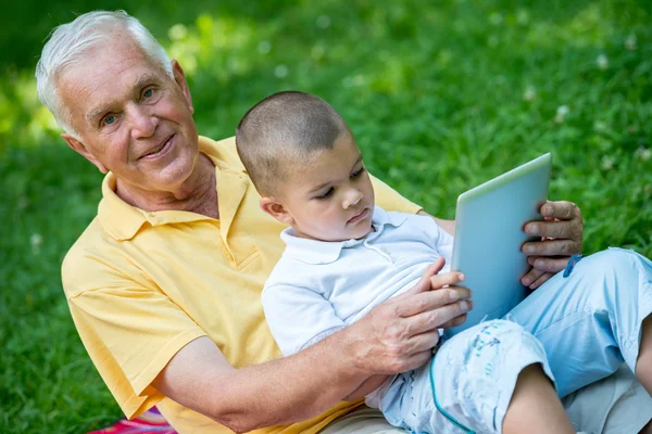 爷爷和小孩在公园里用平板电脑 — 图库照片