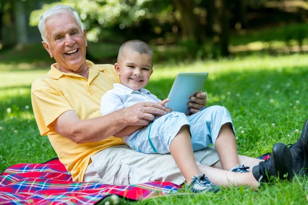 Grandfather and child in park using tablet — Stock Photo, Image