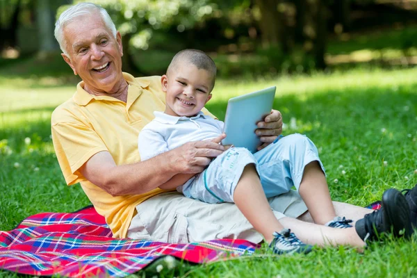 爷爷和孩子在公园里使用平板电脑 — 图库照片