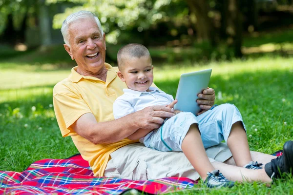 Grandfather and child in park using tablet — Stock Photo, Image