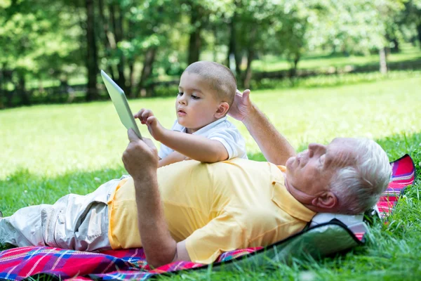 Grandfather and child in park using tablet — Stock Photo, Image