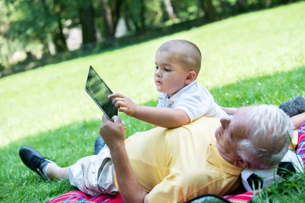 Grandfather and child in park using tablet — Stock Photo, Image