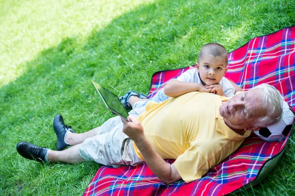 Avô e criança no parque usando tablet — Fotografia de Stock