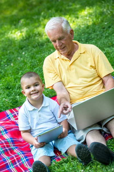 快乐的老爷爷和小孩在公园里用手提电脑 — 图库照片