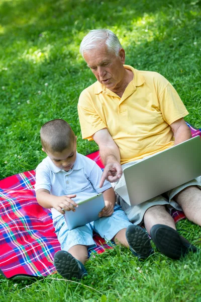 Dědeček a dítě používat notebook a tablet počítač — Stock fotografie