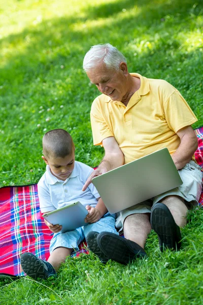 Dziadek i dziecko za pomocą komputera laptop i tabletki — Zdjęcie stockowe