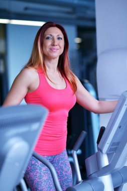 Spor salonunda koşu bandında egzersiz yapan kadın.