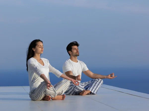 Jeune couple pratiquant le yoga — Photo