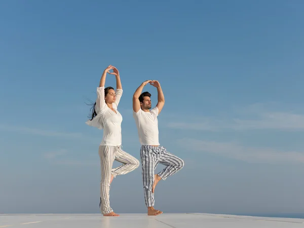 Jovem casal praticando ioga — Fotografia de Stock