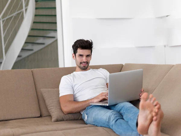 Ung man hemma arbetar på bärbar dator — Stockfoto