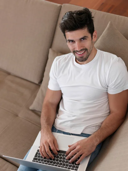 Чоловік розслабляється на дивані з ноутбуком — стокове фото