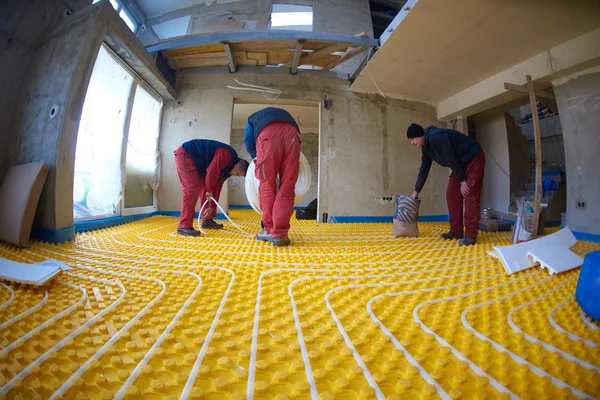 Trabajadores instalando sistema de calefacción por suelo radiante — Foto de Stock