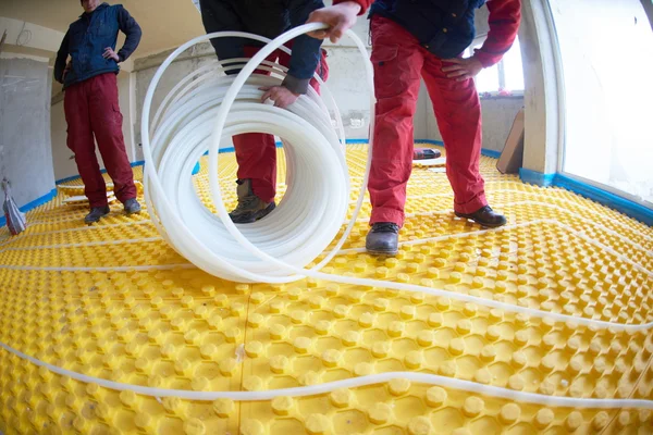 Trabalhadores que instalam sistema de aquecimento radiante — Fotografia de Stock