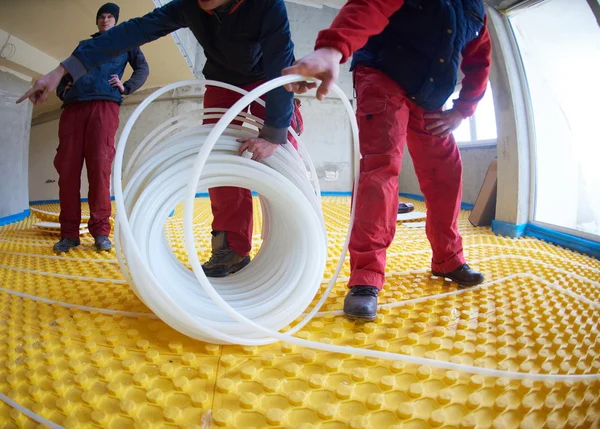 Trabajadores instalando sistema de calefacción por suelo radiante — Foto de Stock