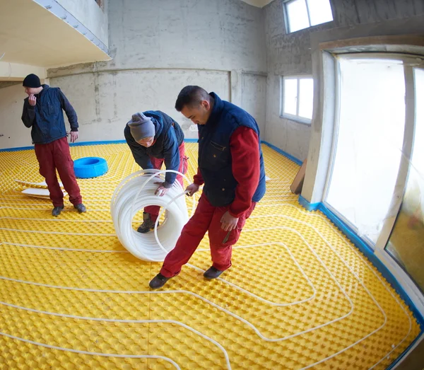 Workers installing underfloor heating system — Stock Photo, Image