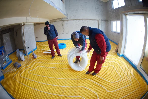 Trabajadores instalando sistema de calefacción por suelo radiante — Foto de Stock