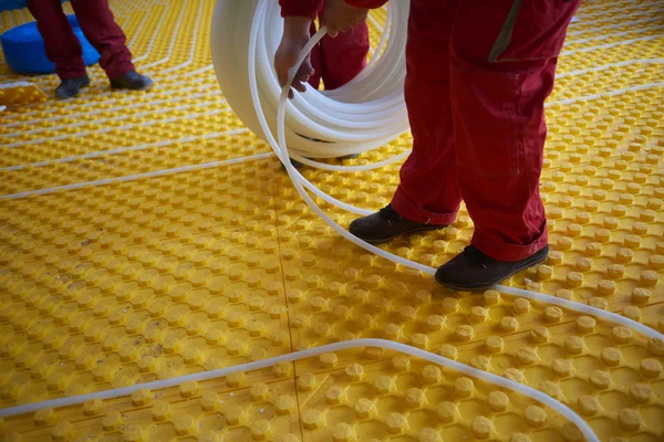 Trabajadores instalando sistema de calefacción por suelo radiante —  Fotos de Stock