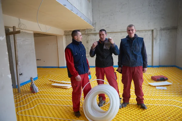 Trabajadores instalando sistema de calefacción por suelo radiante — Foto de Stock