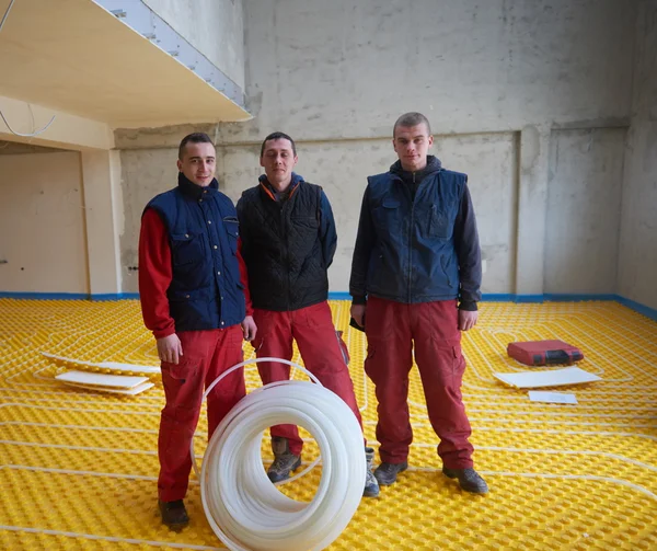 Trabajadores instalando sistema de calefacción por suelo radiante — Foto de Stock