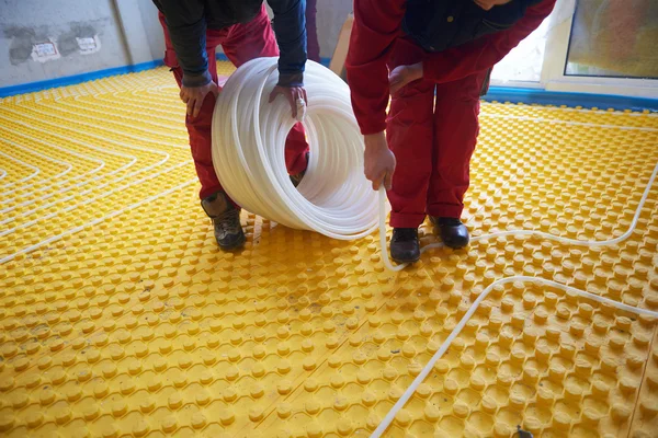 Trabajadores instalando sistema de calefacción por suelo radiante —  Fotos de Stock