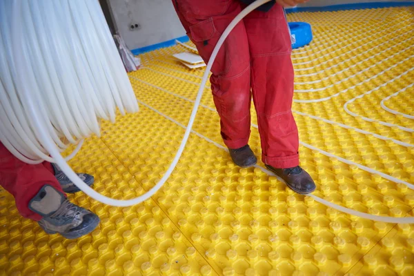 Trabajadores instalando sistema de calefacción por suelo radiante — Foto de Stock