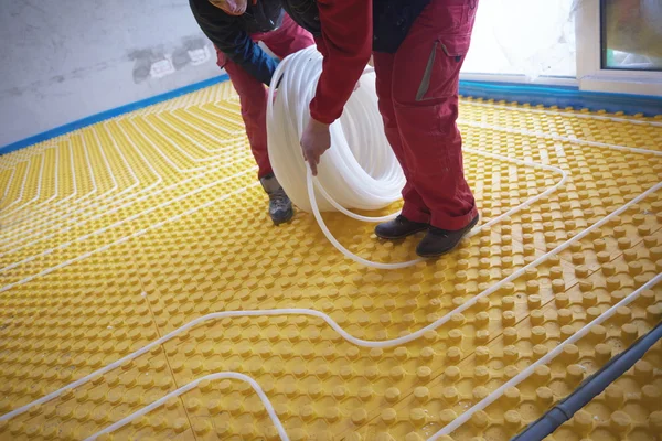 Trabajadores instalando sistema de calefacción por suelo radiante —  Fotos de Stock