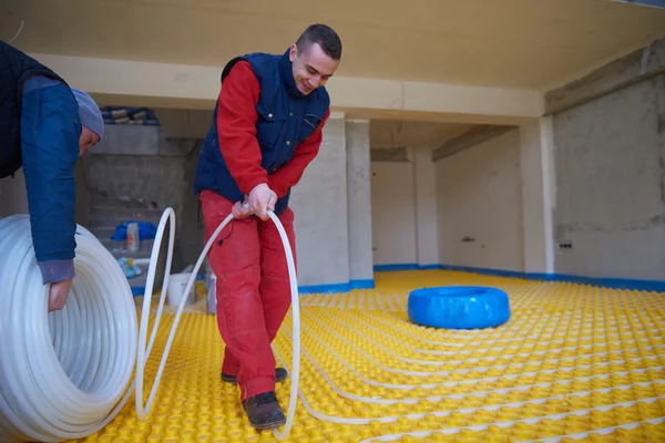 Trabalhadores que instalam sistema de aquecimento radiante — Fotografia de Stock