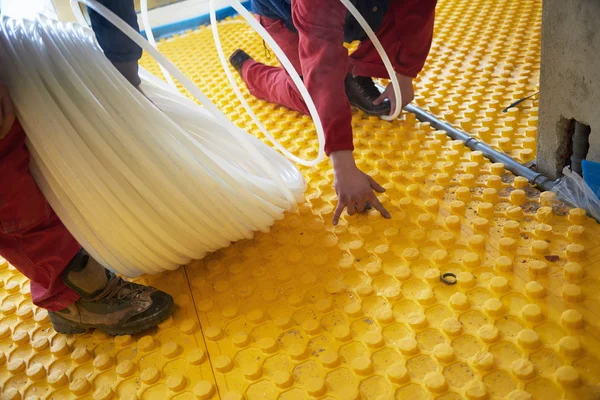 Trabajadores instalando sistema de calefacción por suelo radiante —  Fotos de Stock