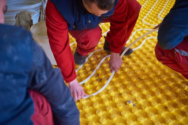 Trabajadores instalando sistema de calefacción por suelo radiante — Foto de Stock