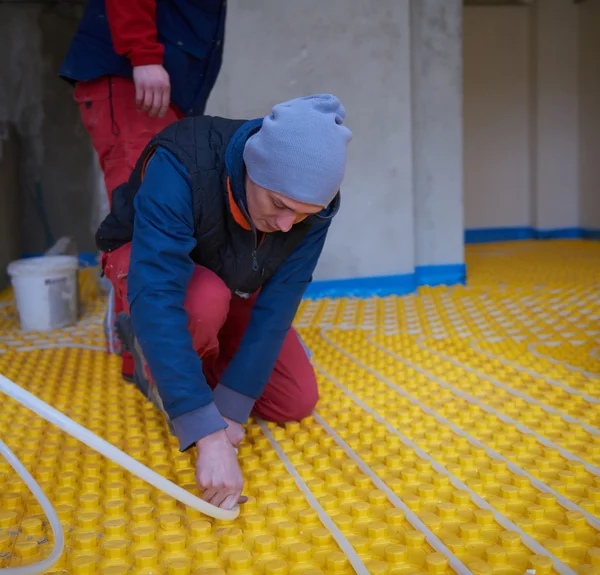 Trabajadores instalando sistema de calefacción por suelo radiante — Foto de Stock