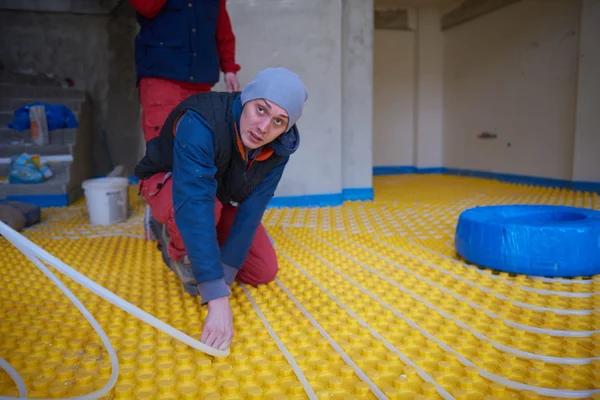 Trabajadores instalando sistema de calefacción por suelo radiante — Foto de Stock